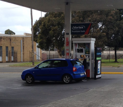 A young woman filling up her blue Volkswagen